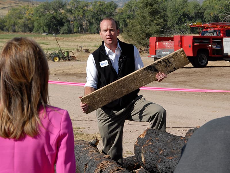 Andy Stauffer showing KRDO NewsChannel 13 a board milled from a log scorched in the Black Forest fire
