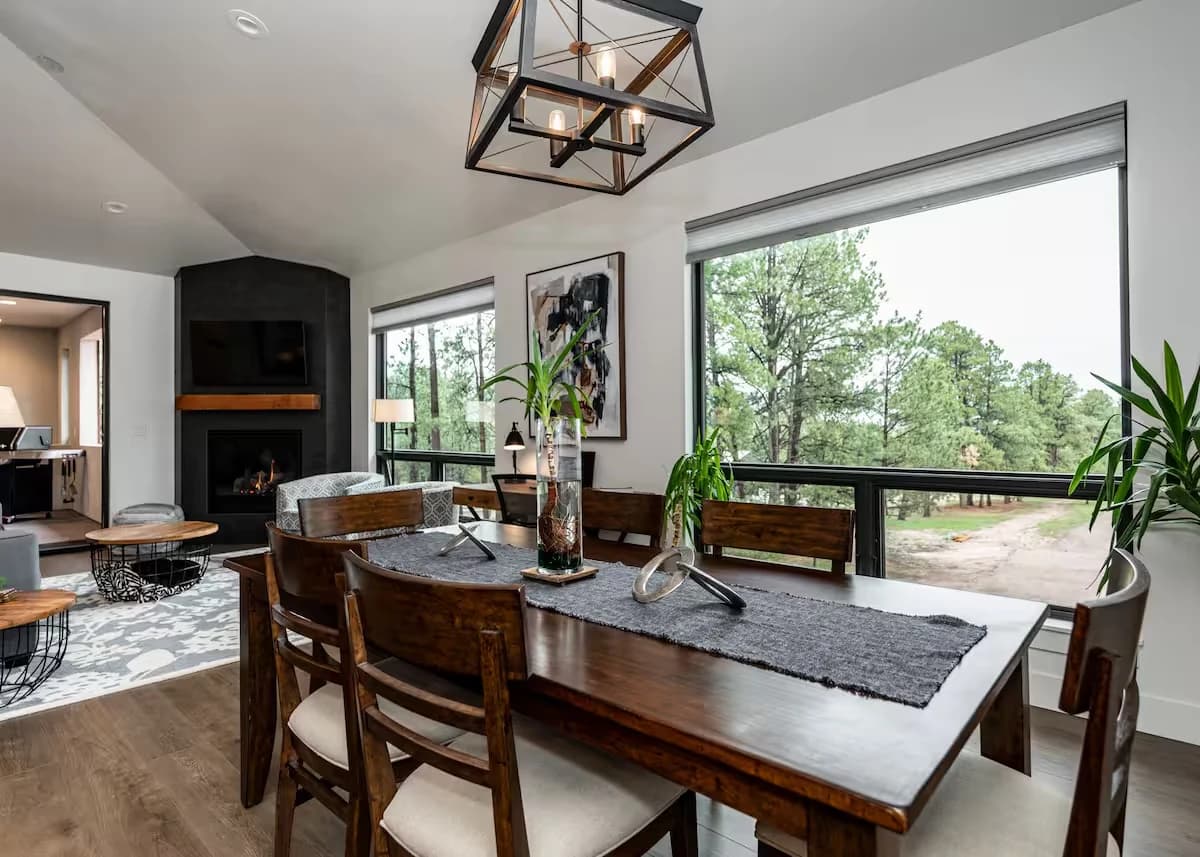 Dining and living area of the Black Forest guest house with a gas fireplace and large windows looking into the pines