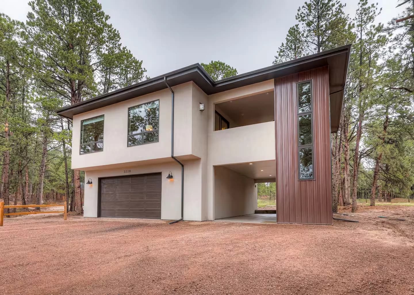 Two-story guest house with stucco walls and a covered upper patio among ponderosa pines in Black Forest, Colorado Springs, designed and built by Andy Stauffer