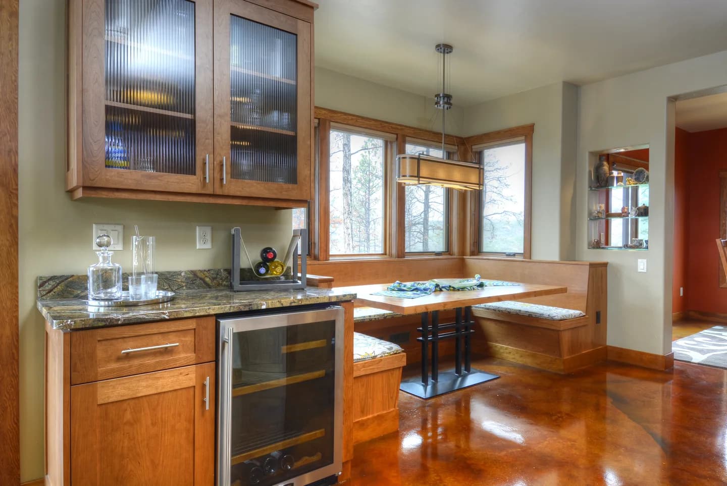 Beverage bar with granite counter, undercounter wine refrigerator and built-in banquette beyond.