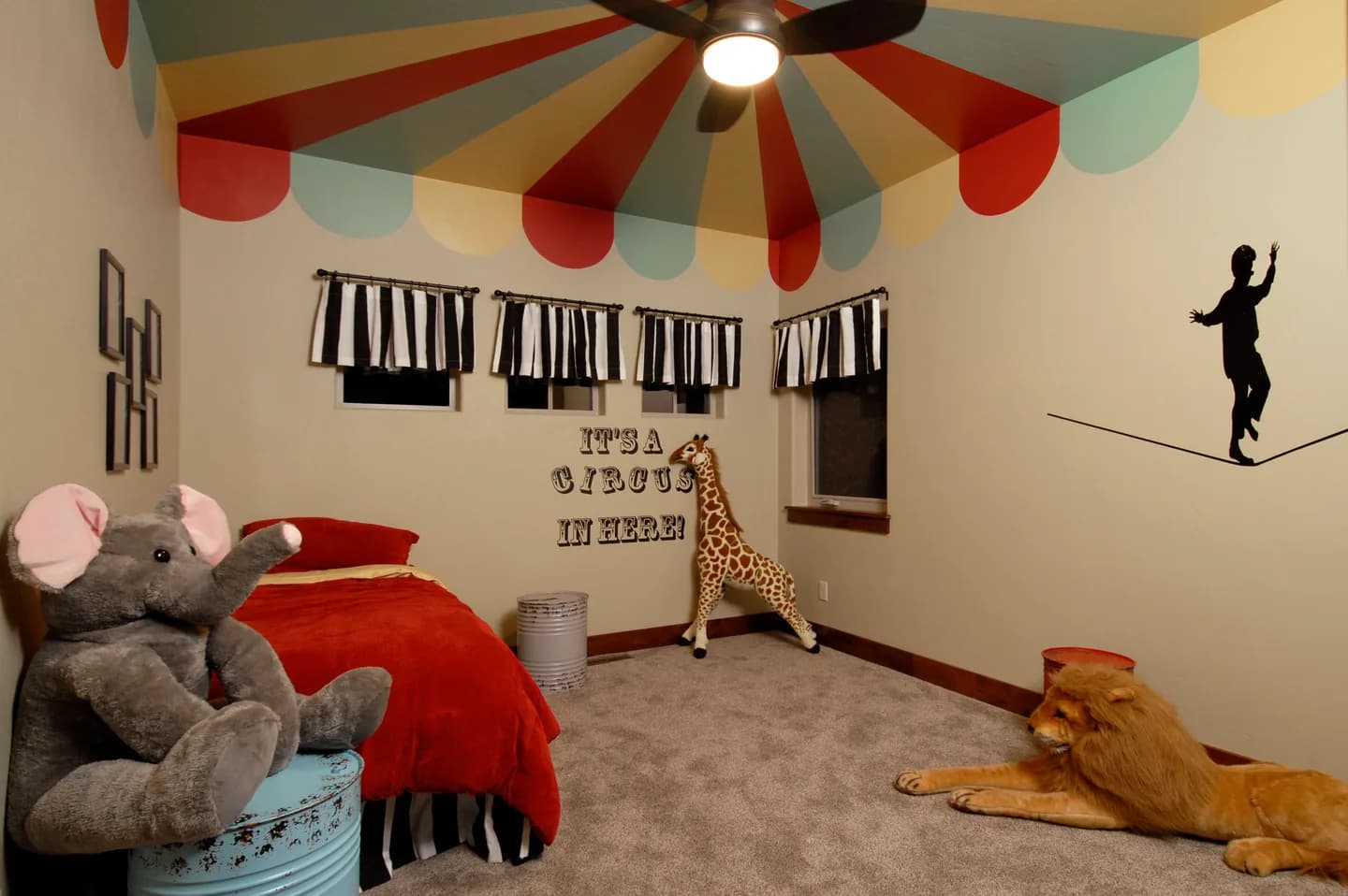 Children's bedroom with circus-tent painted ceiling, custom wall graphics and plush animals.