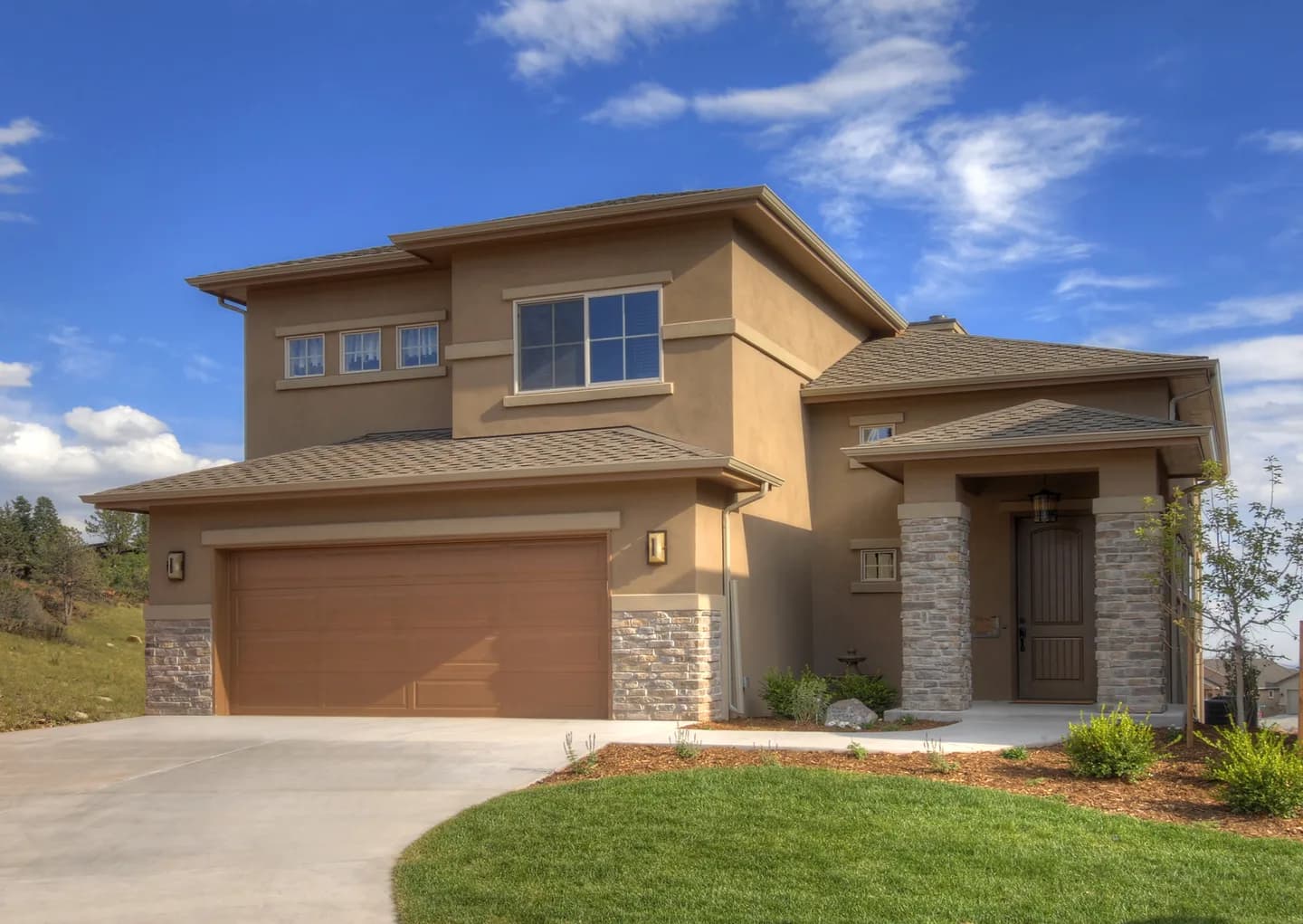 Two-story stucco and stone custom home with three-car garage, arched entry and manicured front lawn.