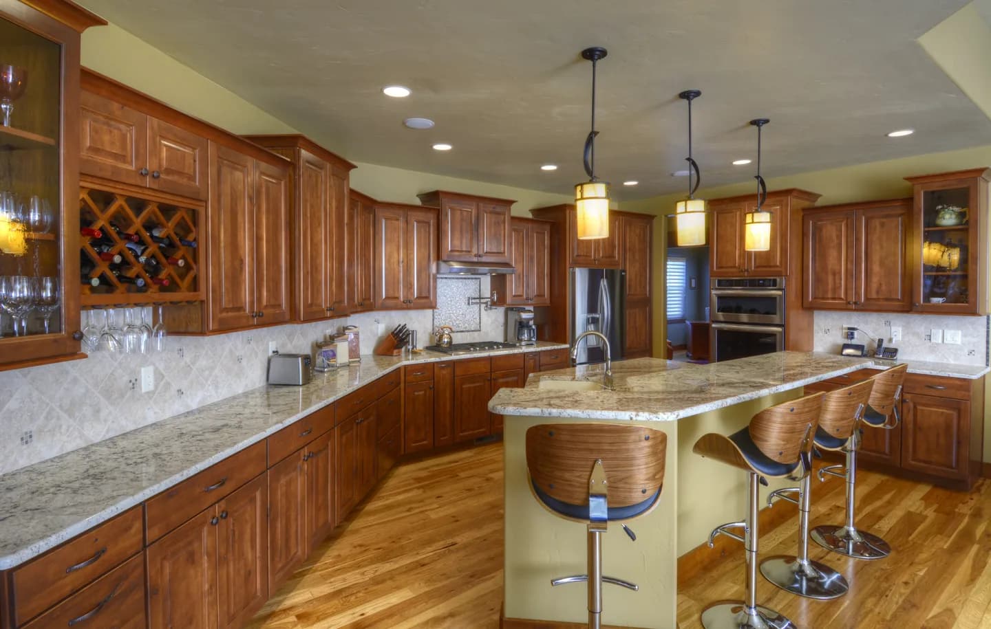 Custom kitchen with cherry cabinetry, granite counters, wine rack and curved island bar seating.