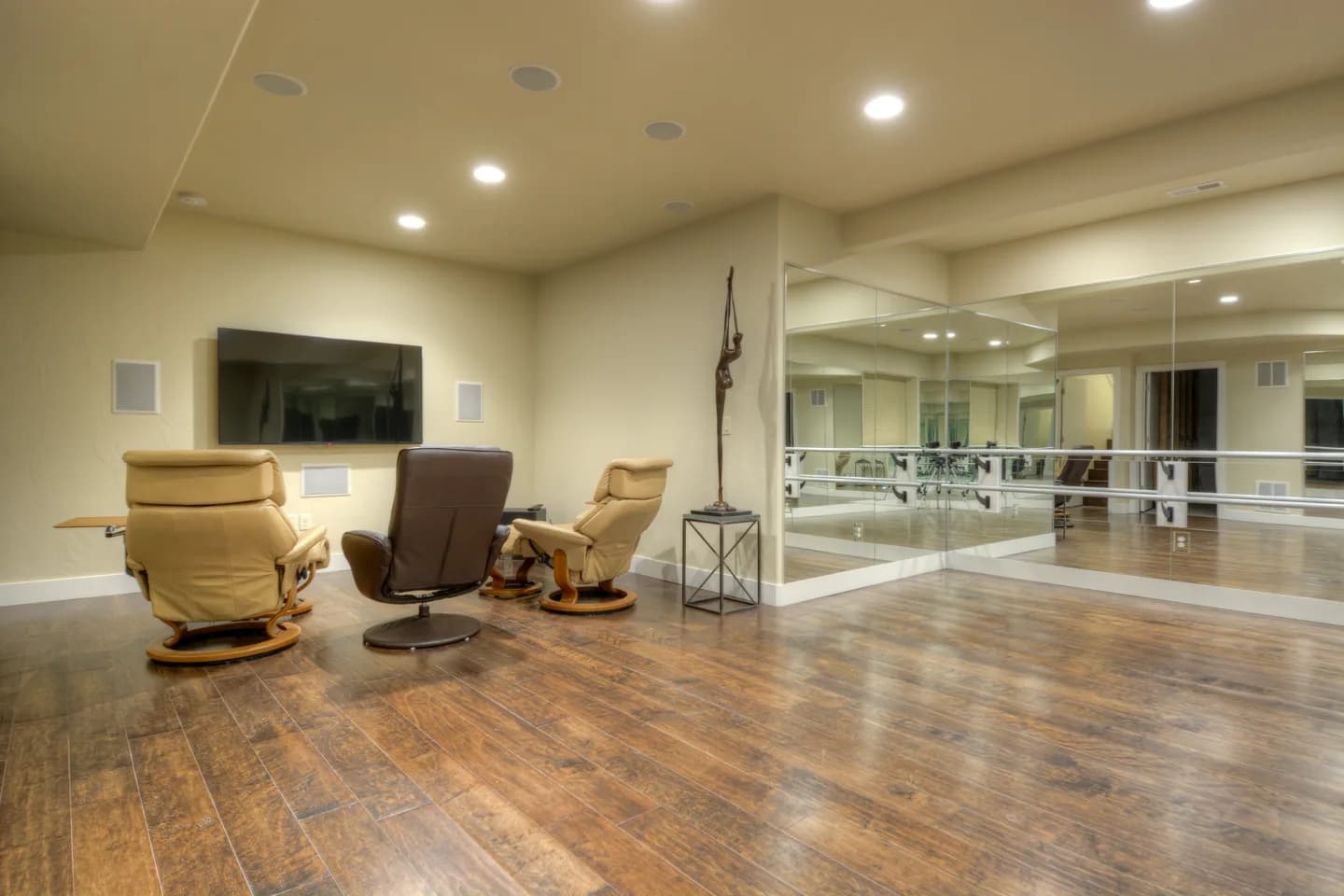 Lower-level exercise and media room with mirrored wall, ballet barre and recliner seating.