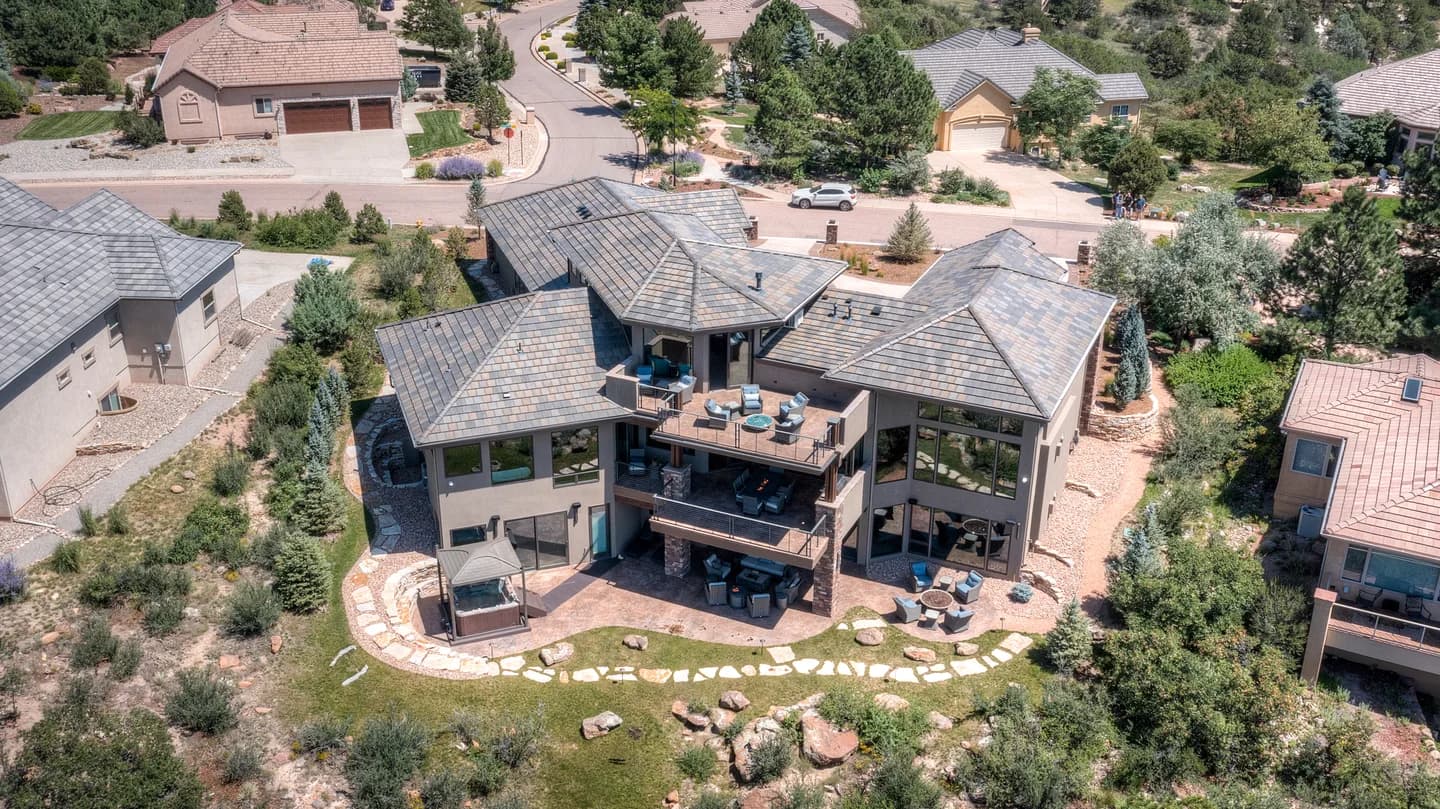 Overhead aerial of the home's rear decks, walkout patio and hillside landscaping in a golf-course neighborhood