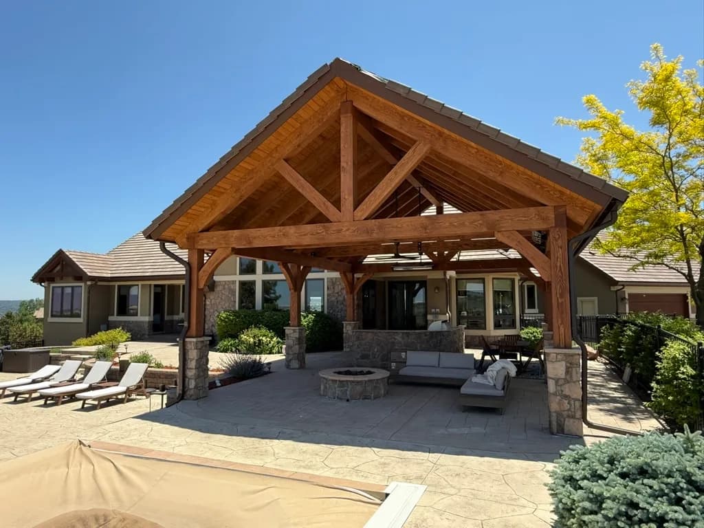 A heavy-timber pavilion with stone columns and an outdoor kitchen, built by Stauffer & Sons in Parker