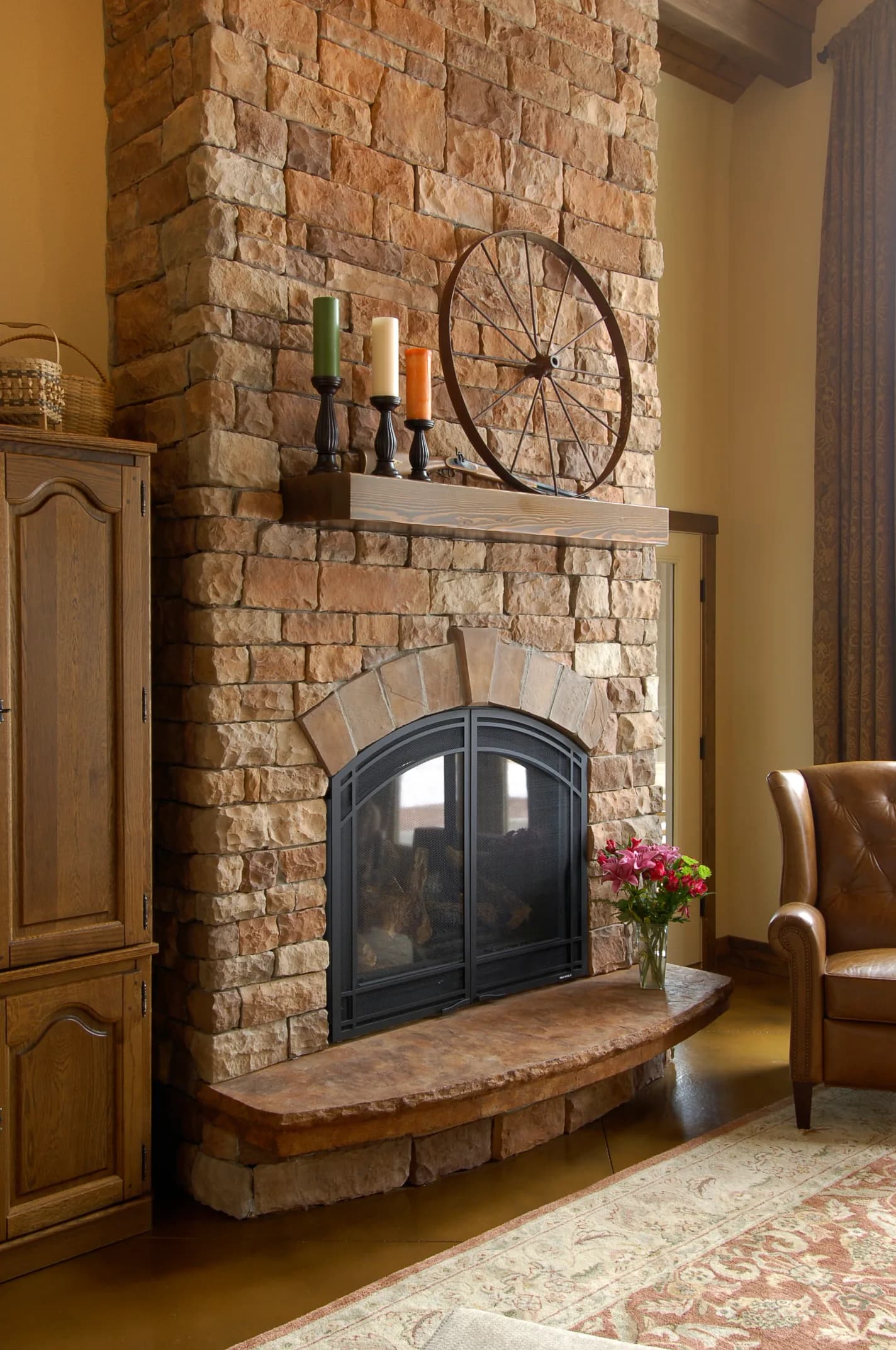 Floor-to-ceiling stacked-stone fireplace with arched firebox, timber mantel and curved raised stone hearth