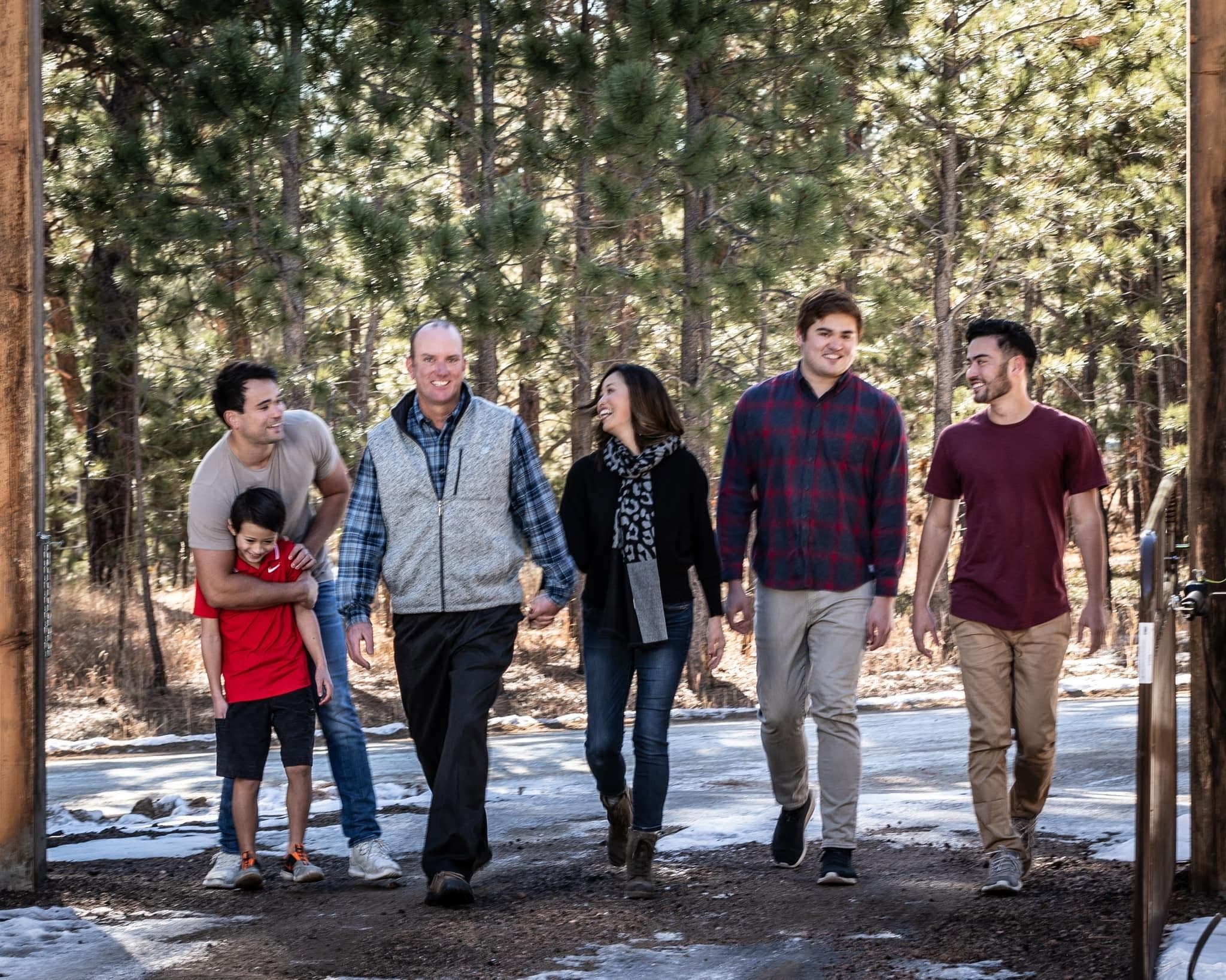 The Stauffer family walking together beneath the pines
