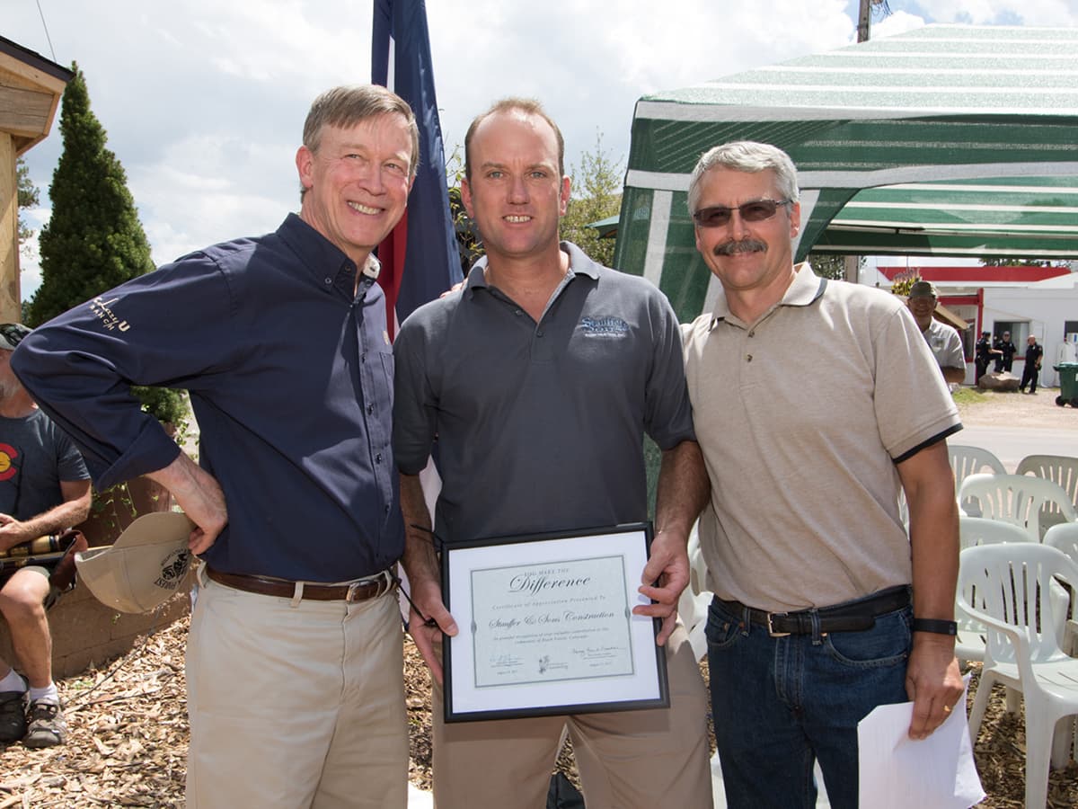 Andy Stauffer (center) with Colorado Gov. John Hickenlooper (left), honored for rebuilding after the Black Forest fire